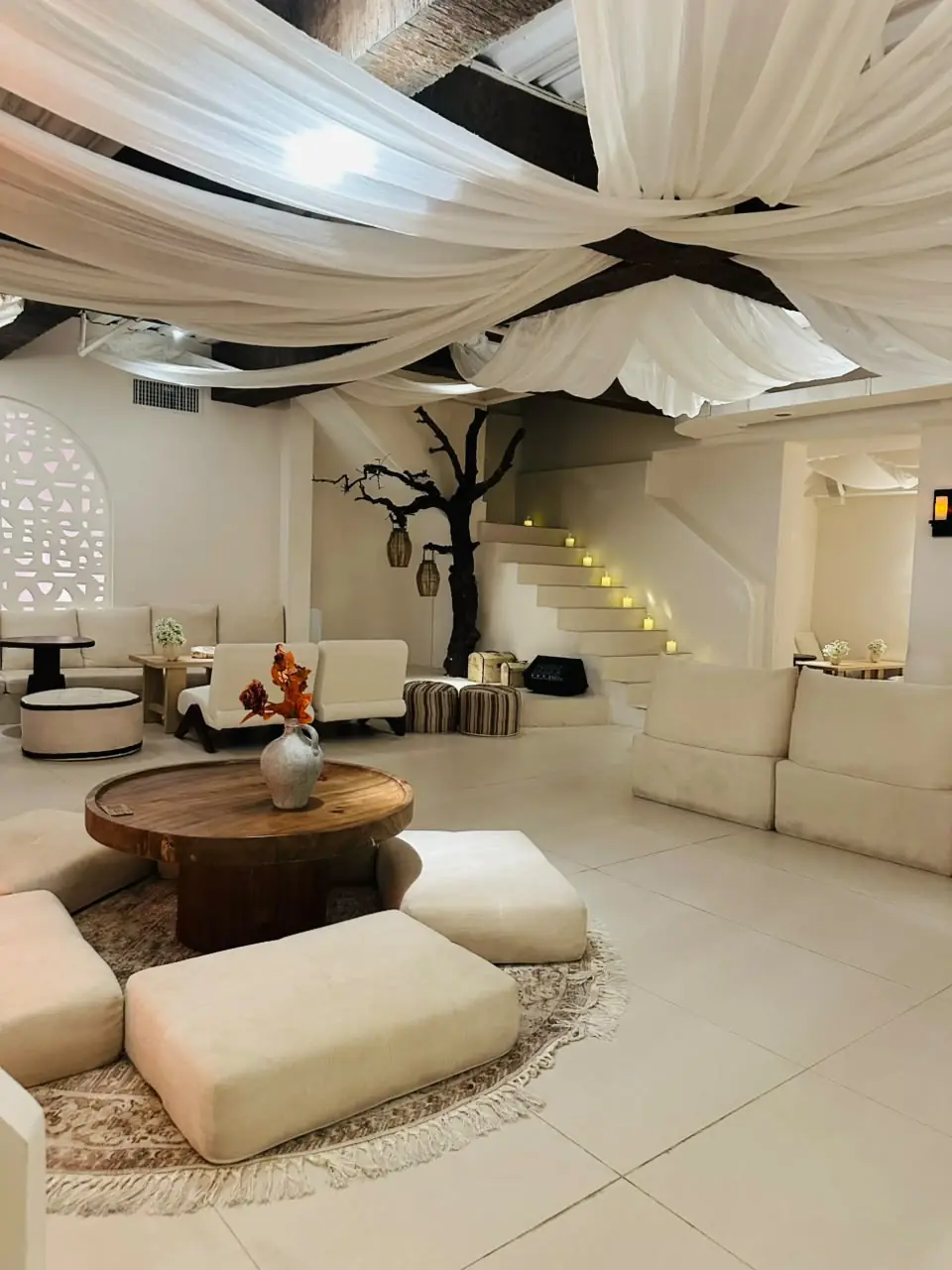 Lounge with low seating, cushions and a tree sculpture